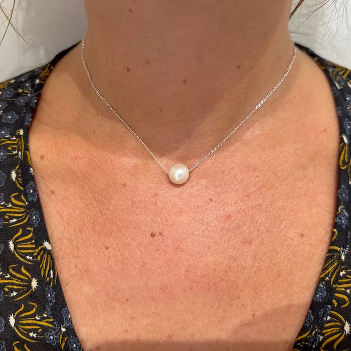 Chain necklace with a white freshwater pearl worn around the neck