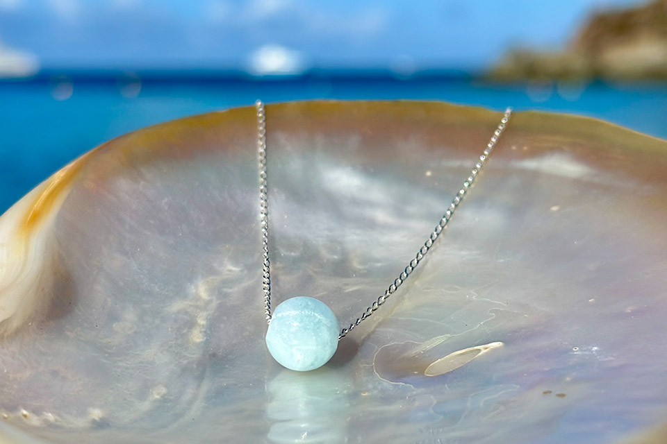 925 sterling silver chain necklace with a round light blue gemstone displayed on mother-of-pearl