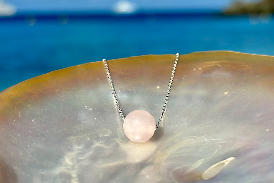 925 sterling silver chain necklace with a round rose quartz displayed on mother-of-pearl