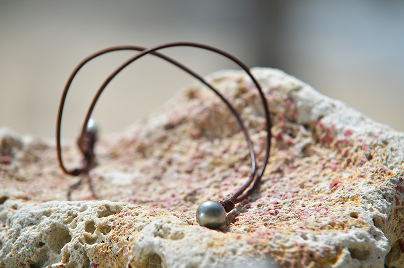 Unisex brown leather pendant necklace with two Tahitian cultured pearls arranged in a loop on coral rock