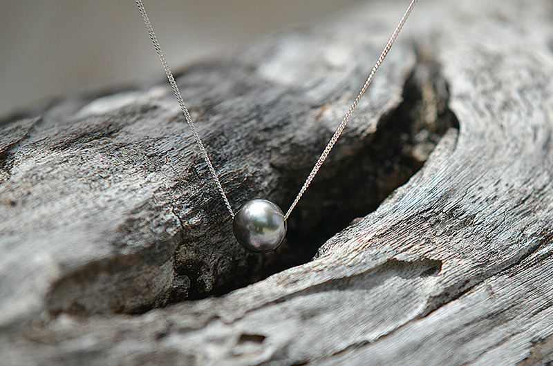 Collier chaîne en argent 925 avec une perle de culture de Tahiti présenté sur du bois flotté