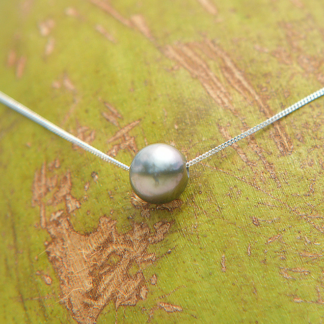 Collier chaîne en argent 925 avec une perle de culture de Tahiti semi-ronde présenté sur une feuille verte