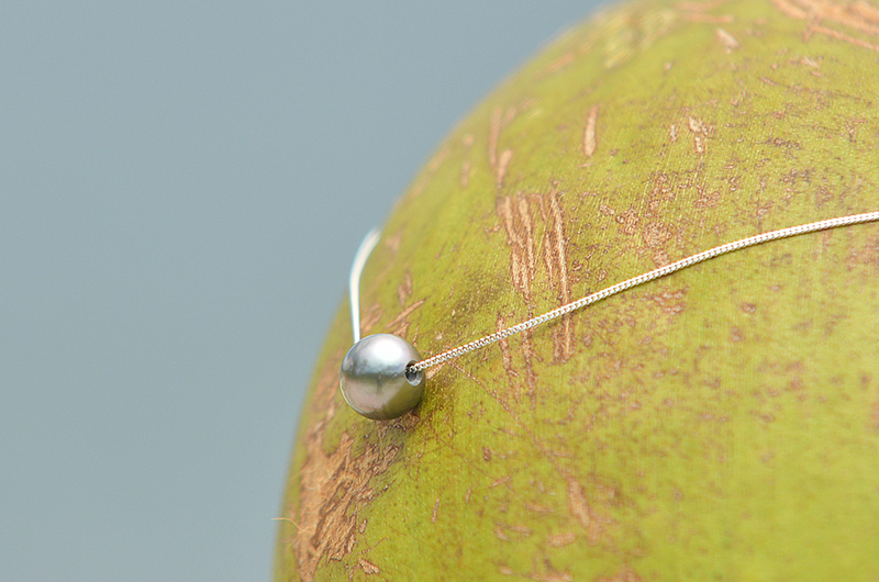 Collier chaîne en argent 925 avec une perle de culture de Tahiti présenté en vue large sur une feuille verte