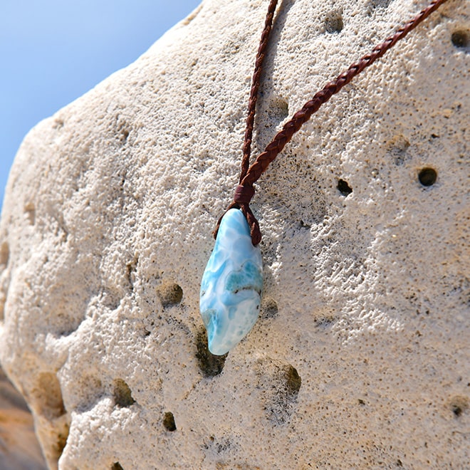 Braided kangaroo leather necklace with a Larimar pendant displayed on a rock