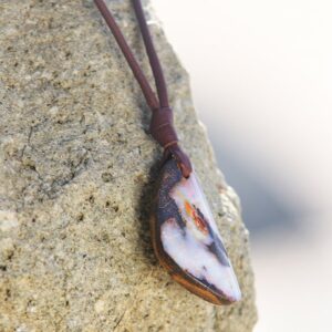 Brown leather necklace with an Australian opal pendant displayed on a rock