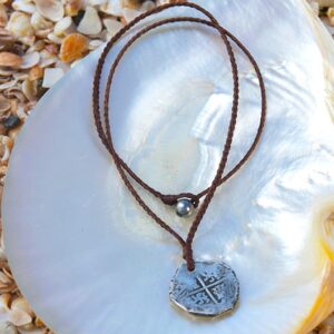 Collier pendentif en cuir tressé avec ancienne monnaie de 8 réaux en argent et perle de Tahiti présenté sur une nacre