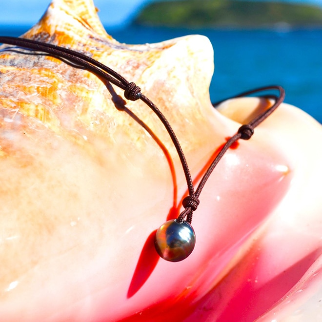 Collier pendentif ajustable sur cordon marron avec une perle de culture de Tahiti de 10,5 mm présenté sur un coquillage