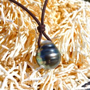 Close-up of the 13.5 mm Tahitian cultured pearl on the pendant necklace displayed on coral