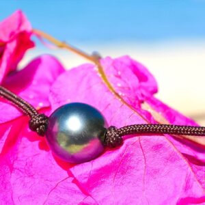 Close-up of the 9.5 mm semi-round Tahitian cultured pearl on the choker necklace displayed on bougainvillea flowers