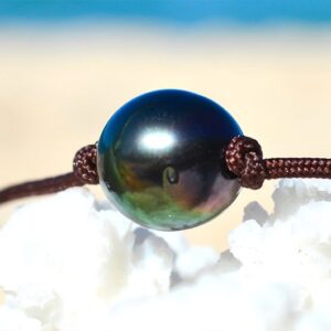 Close-up of the green 10.5 mm semi-round Tahitian cultured pearl on the choker necklace displayed on white coral