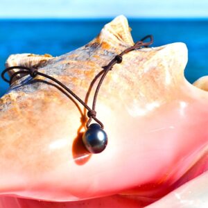 Adjustable pendant necklace with a 13 mm drop-shaped Tahitian cultured pearl displayed on a seashell facing the sea