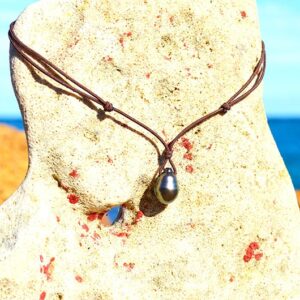 Full view of the adjustable pendant necklace with a 12 mm drop-shaped Tahitian cultured pearl displayed on a rock facing the sea