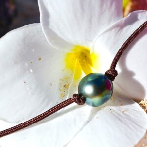 Close-up of the 9 mm semi-round Tahitian cultured pearl on the choker necklace displayed on white and pink flowers