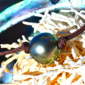 Close-up of the 10 mm semi-round Tahitian cultured pearl on the choker necklace displayed on mother-of-pearl