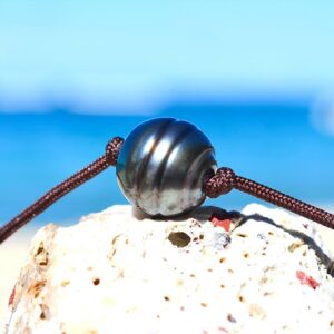 Close-up of the 11 mm Tahitian cultured pearl and brown cord on the choker necklace displayed on white coral