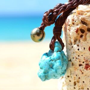 Close-up of the turquoise, Tahitian cultured pearl and braided leather on the necklace facing the sea