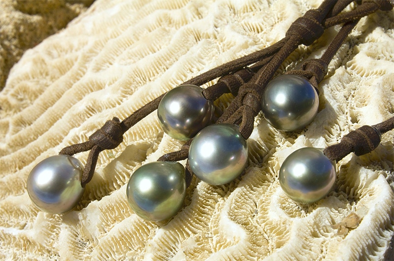 Close-up of the five main 10.5 mm Tahitian cultured pearls and brown leather on the cluster necklace displayed on coral