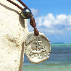 Leather pendant necklace with an antique Spanish four-reales coin and two Tahitian cultured pearls displayed facing the sea