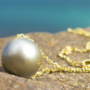 Close-up of the round 13 mm Tahitian cultured pearl and 14-karat gold chain on the necklace arranged on a rock