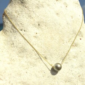 Full view of the choker necklace with a 14-karat gold chain and 13 mm Tahitian cultured pearl displayed facing the sea