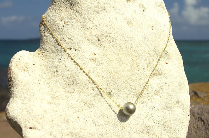 Vue d’ensemble du collier ras du cou avec une chaîne en or 14 carats et une perle de culture de Tahiti de 13 mm présenté face à la mer