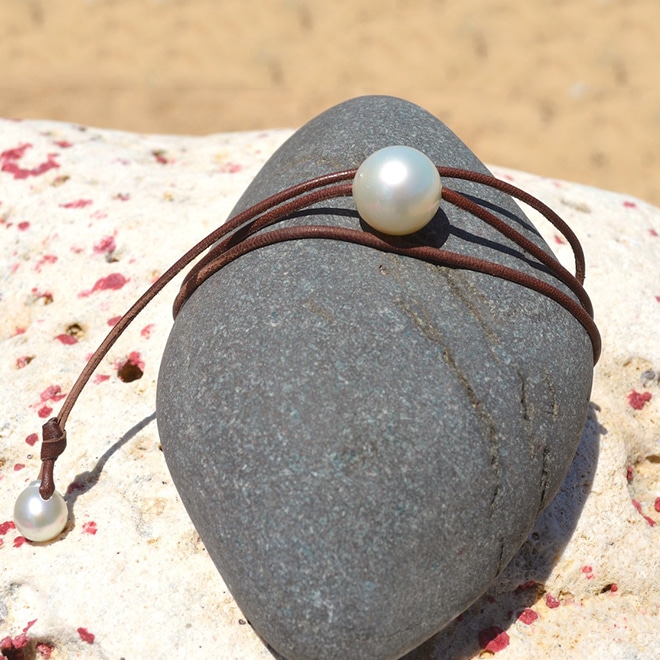 Collier ras du cou ajustable avec une perle blanche des mers du Sud de 16 mm et une perle de fermoir présenté sur une roche