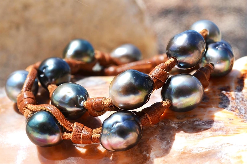 Close-up of the 17 Tahitian cultured pearls and brown leather of the convertible jewelry worn as a double-wrap bracelet