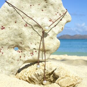 Adjustable leather long necklace with three white South Sea cultured pearls displayed on coral at the beach