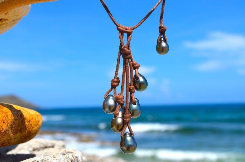 Close view of the cluster of six Tahitian cultured pearls and brown leather of the necklace facing the sea