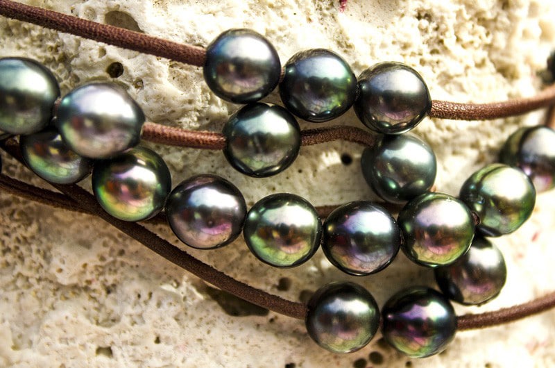 Close-up of the semi-baroque Tahitian pearls with green and aubergine overtones and the brown leather of the long necklace