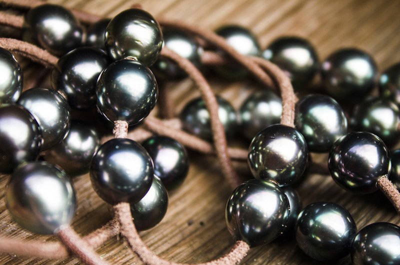 Detail of the semi-baroque Tahitian cultured pearls and brown leather setting of the long necklace displayed on mother-of-pearl