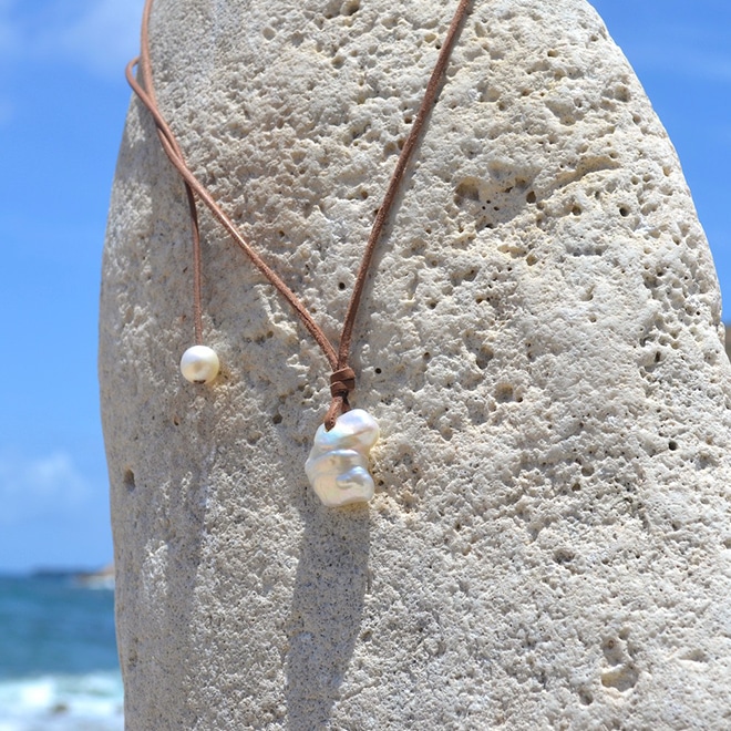 Adjustable leather pendant necklace with a large baroque freshwater cultured pearl and an adjustment pearl displayed facing the sea