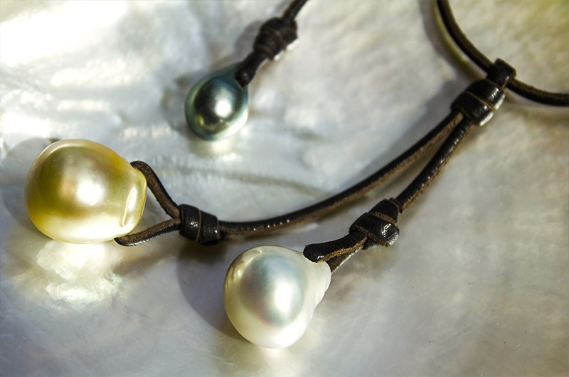 Détail des trois perles de culture d’Australie et de Tahiti et des nœuds du collier grappe présentés sur une nacre