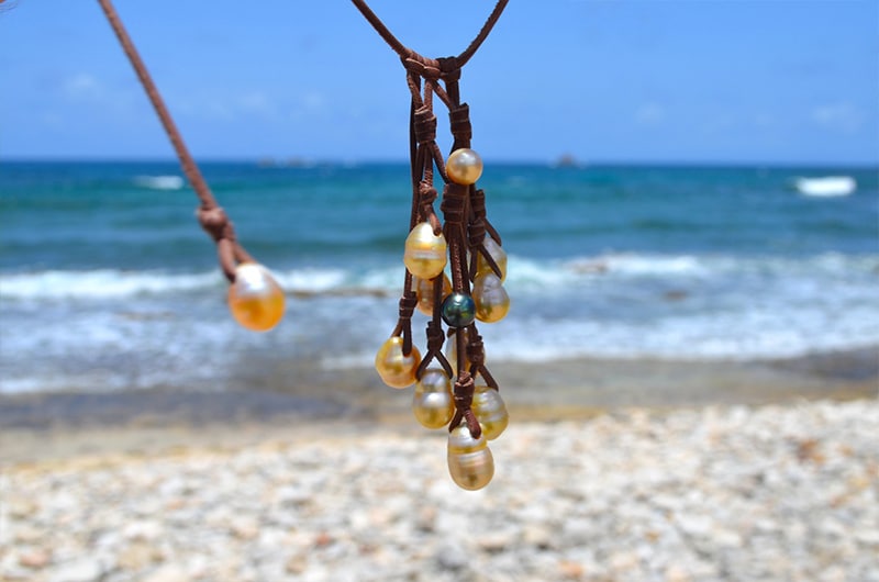 Full view of the cluster necklace with ten golden Australian pearls and its adjustment pearl hanging at the beach