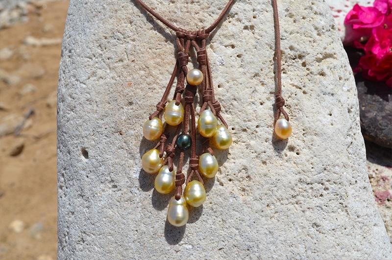 Close-up of the golden Australian pearls, green Tahitian pearl and brown leather knots of the cluster necklace