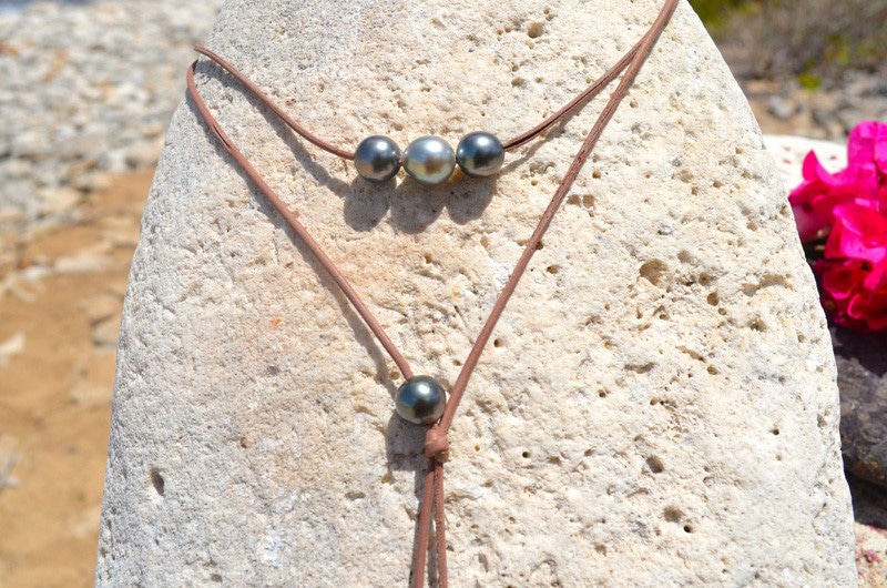 Close view of the seven Tahitian cultured pearls with green, silver and peacock overtones and the brown leather setting of the long necklace