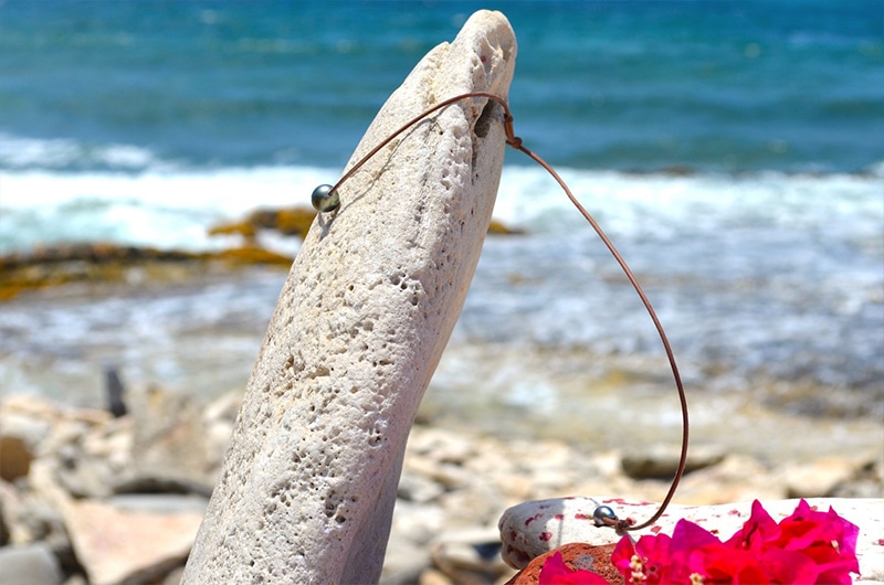 Vue latérale du collier ras du cou en cuir avec ses deux perles de Tahiti face à la mer