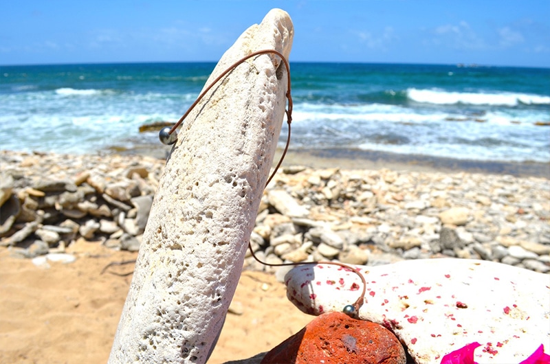 Side view of the leather choker with its two Tahitian pearls facing the sea
