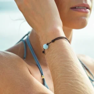 Bracelet ajustable sur cordon noir avec une pierre d’aigue-marine porté au poignet en vue rapprochée