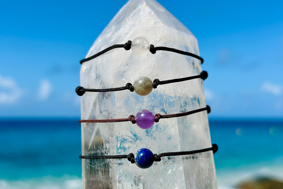 Full view of four adjustable bracelets with a choice of 8 mm gemstones on a crystal facing the sea