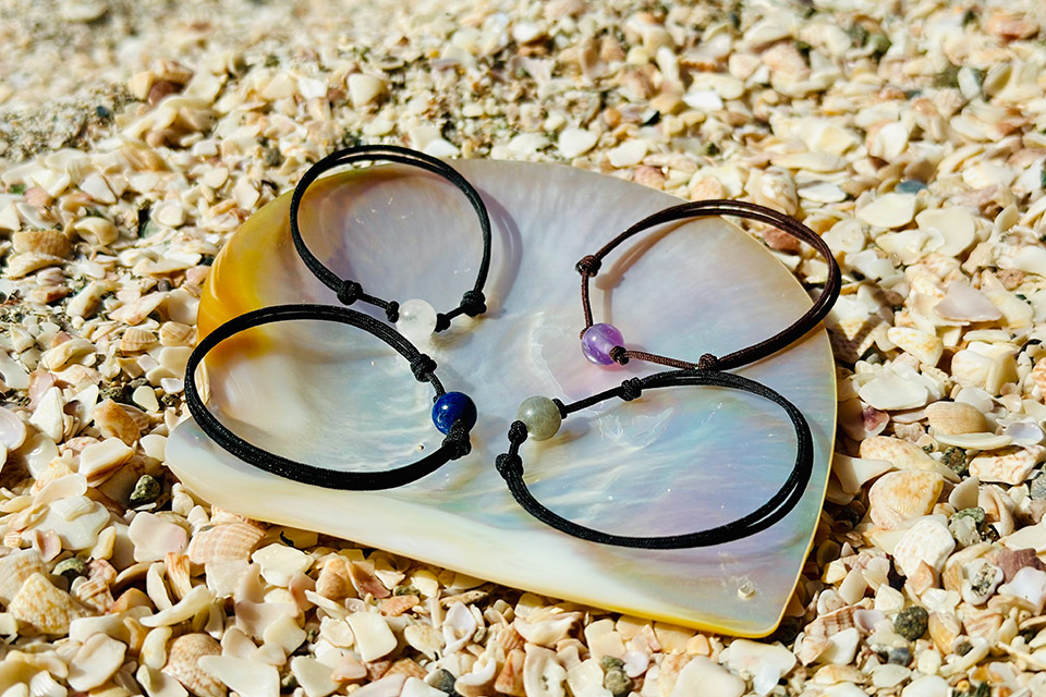 Selection of adjustable bracelets with amethyst, lapis lazuli, aquamarine and labradorite displayed on mother-of-pearl