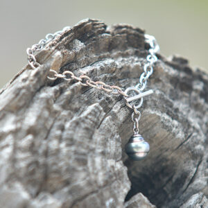 Bracelet chaîne en argent 925 avec une perle de culture de Tahiti cerclée de 11 mm présenté sur du bois