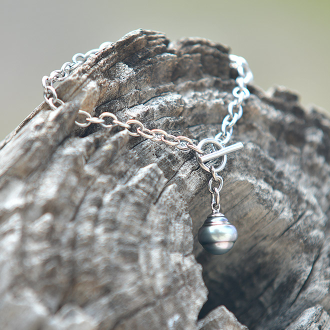 Bracelet chaîne en argent 925 avec une perle de culture de Tahiti cerclée de 11 mm présenté sur du bois