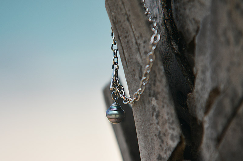 Vue rapprochée de la perle de Tahiti cerclée et de la chaîne en argent 925 du bracelet sur du bois