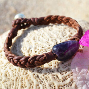 Bracelet en cuir marron tressé à six fils avec améthyste et perle de culture d’Australie présenté sur du corail