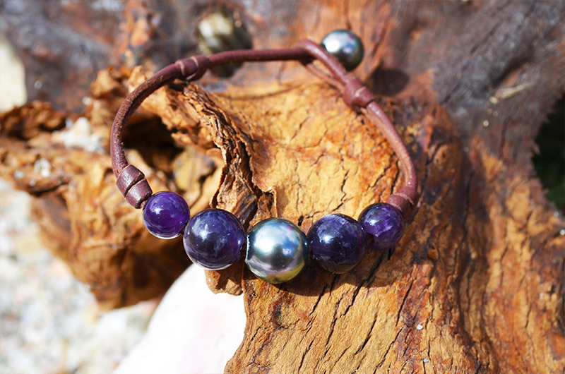 Bracelet en cuir marron avec perle de Tahiti et améthystes présenté sur du bois en vue rapprochée