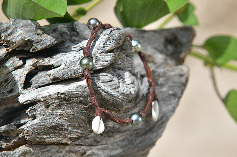 Full view of the bracelet or anklet with seashells and Tahitian pearls displayed on wood