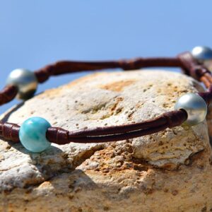 Vue rapprochée du Larimar et des perles de Tahiti du bracelet ou de la chevillère en cuir sur une roche