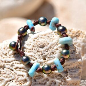 Bracelet en cuir marron avec sept perles de culture de Tahiti et éléments de Larimar présenté sur du corail