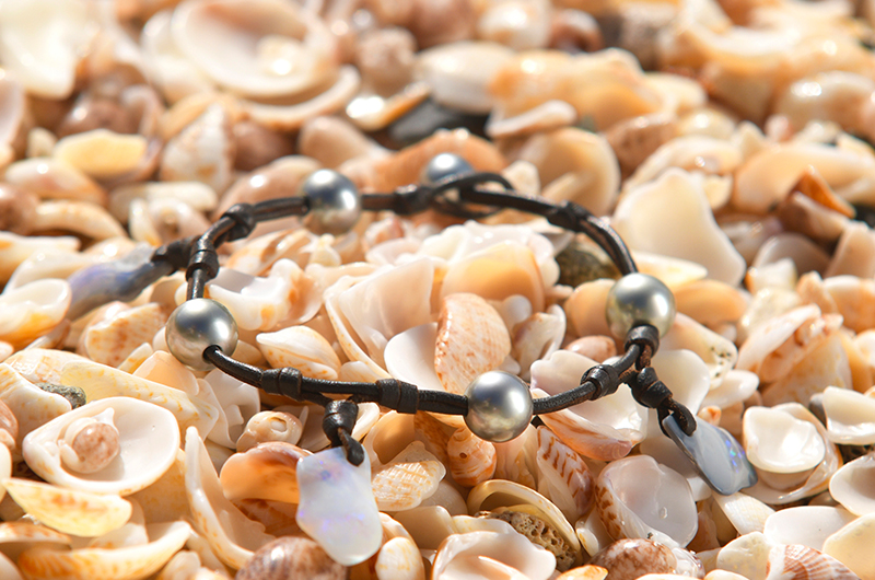 Leather bracelet or anklet with opals and Tahitian pearls displayed on a bed of seashells